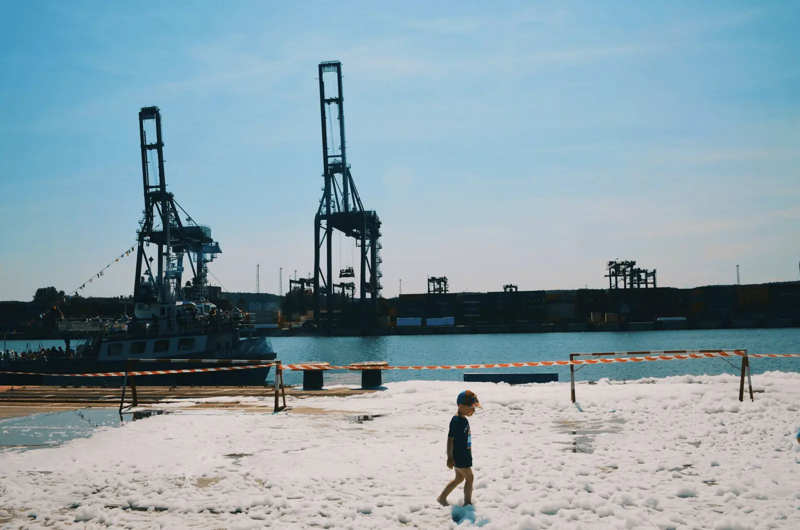Port cranes over a sandy beach